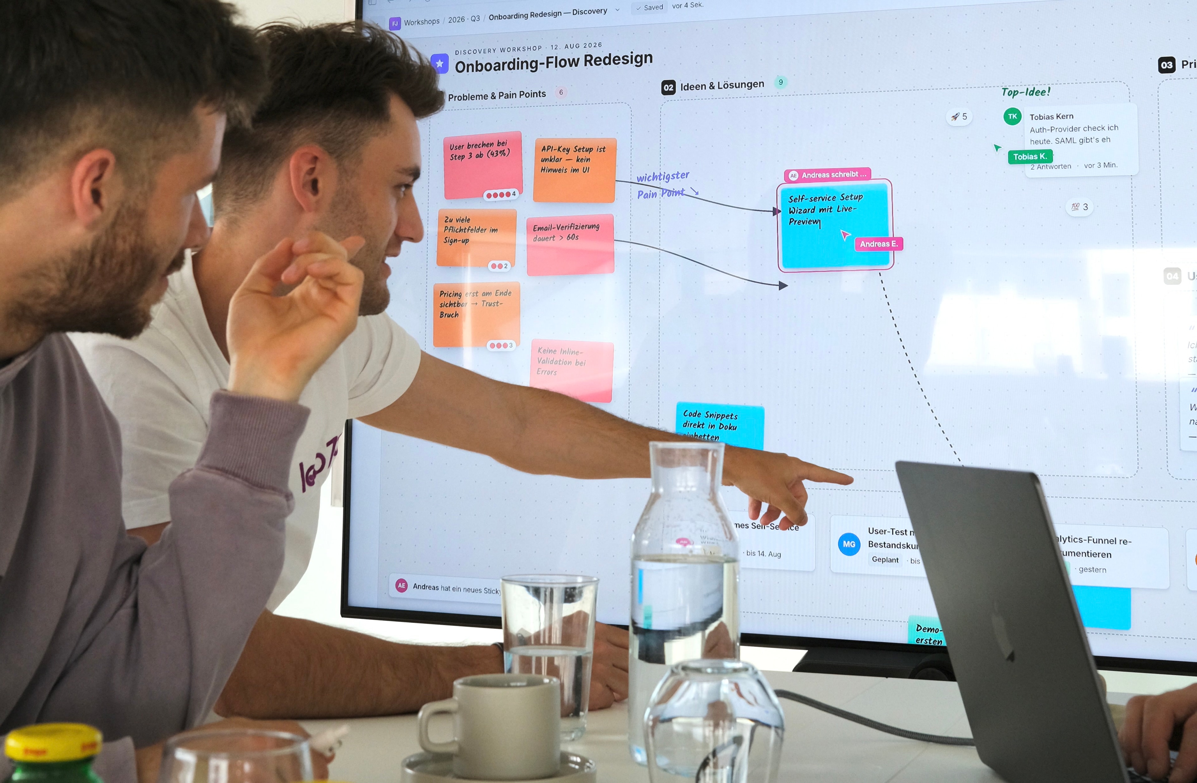 Zwei Personen im Workshop, eine zeigt auf ein Board mit Problemen, Ideen und Prioritäten