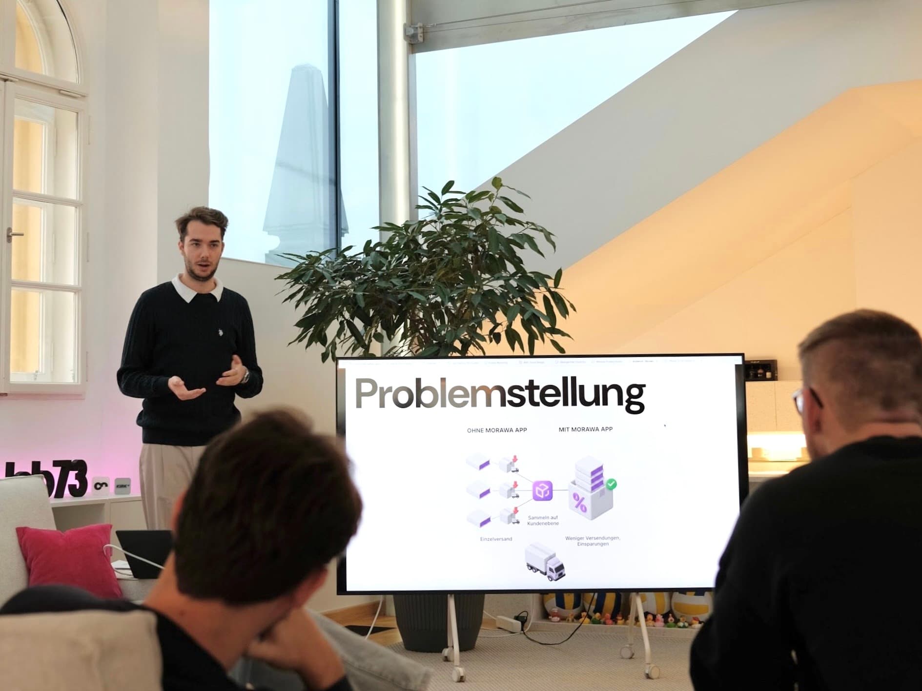 Person aus dem lab73-Team stellt einem kleinen Kreis die Problemstellung eines Kundenprojekts vor